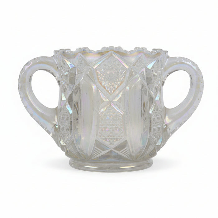 Iridescent glass cup with decorative patterns on a textured surface