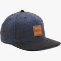 Dark blue Billabong Stacked Up Cap with a black brim and textured fabric, featuring a brown leather-look logo patch on the