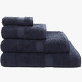 Stack of four folded navy Colibri Imperial Zerotwist bath sheets in varying sizes, showcasing their plush texture.