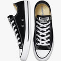 Two black Converse All Star low-top canvas sneakers, one viewed from the side and the other from the top front, featuring