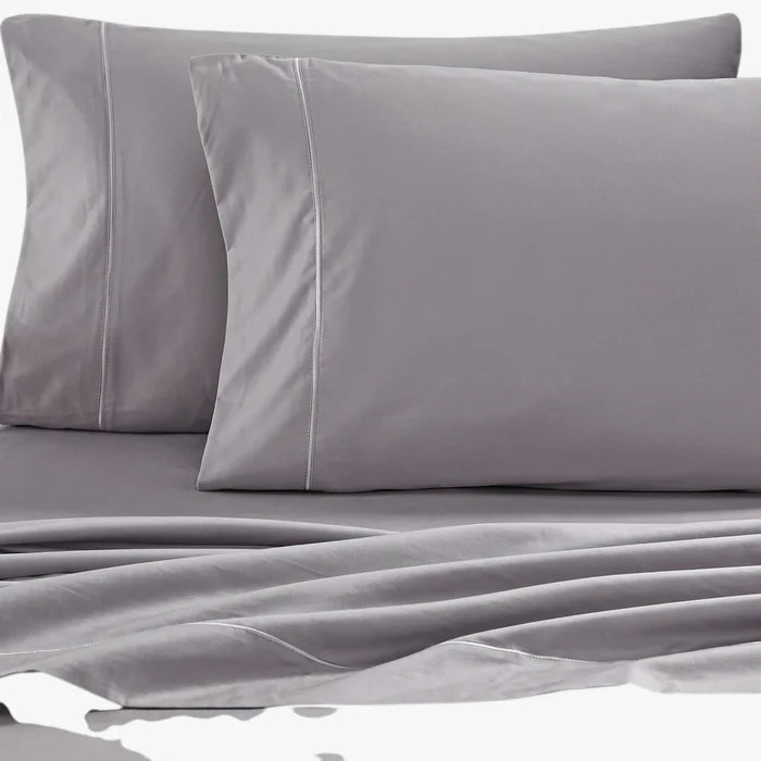 Two grey Cotton Co 400 Thread Oxford 50x90 pillowcases with white stitching, displayed on a matching grey fitted sheet.