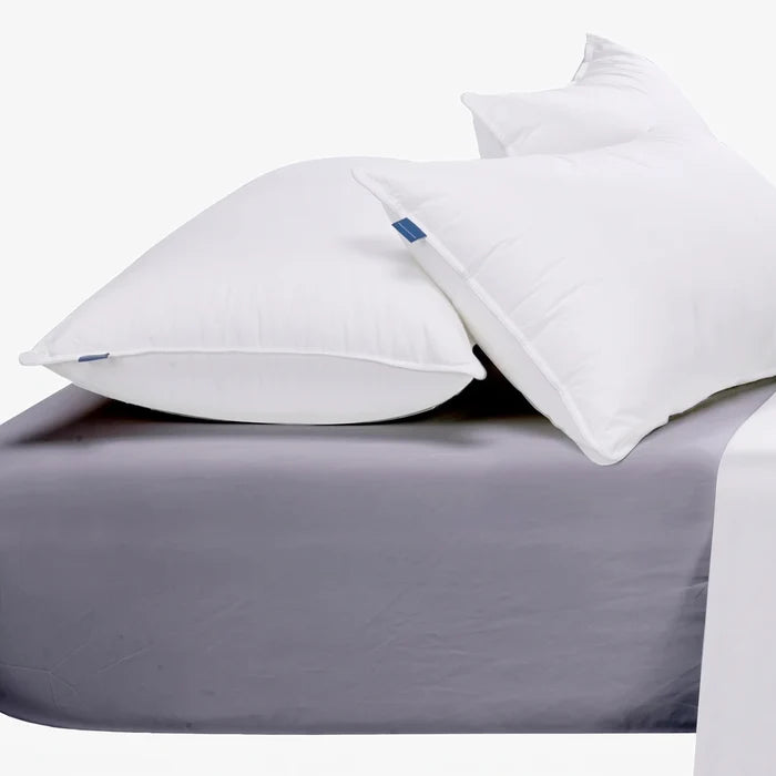A grey Cotton Co 400 thread count queen fitted sheet with two white pillows resting on it.
