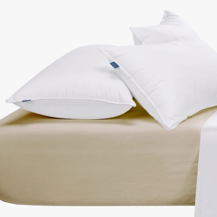 Two white pillows rest on a stone cotton sateen queen extra fitted sheet, showcasing its smooth texture.