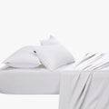 Cotton Co 400 thread count queen extra fitted sheet in white, displayed on a bed with two pillows.