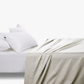 Cream Cotton Co 400 thread count Queen flat sheet draped over a bed with two white pillows.
