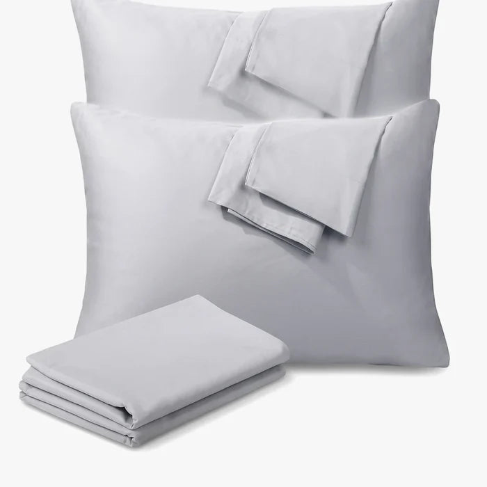 A pair of soft grey standard pillowcases from Cotton Co, neatly folded on top of each other and next to a matching grey