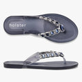 A top-down and side view of Holster Women's Miranda jelly sandals in clear and midnight blue with decorative silver and blue