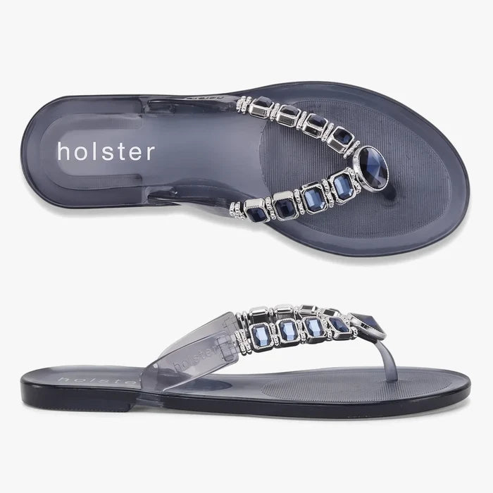 A top-down and side view of Holster Women's Miranda jelly sandals in clear and midnight blue with decorative silver and blue