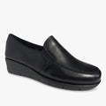 A single black Hush Puppies Womens Grecia slip-on shoe, made of smooth leather with a low wedge heel, shown in a side view.