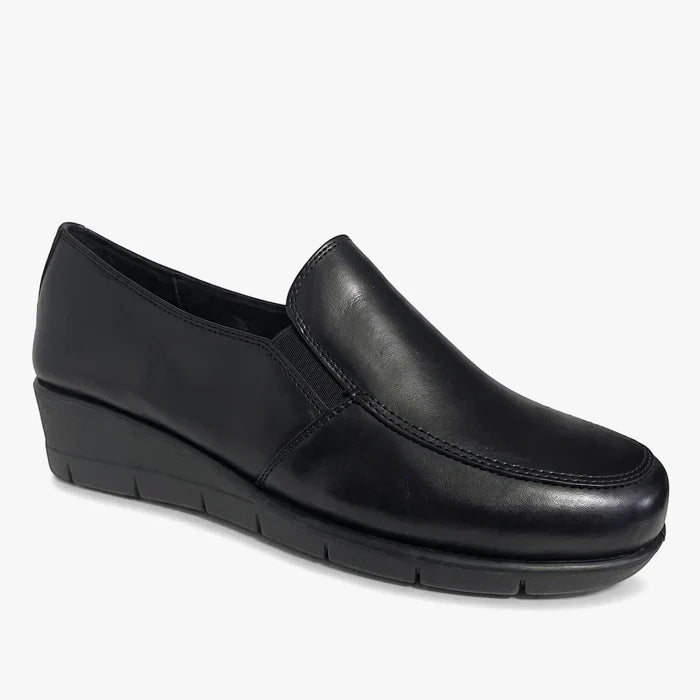 A single black Hush Puppies Womens Grecia slip-on shoe, made of smooth leather with a low wedge heel, shown in a side view.