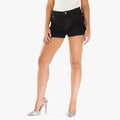 A female model showcasing Miss Black Brandy 1 distressed denim shorts in black, paired with silver pointed-toe high heels.