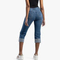 Rear view of a model wearing Sissy Boy Ryder high waist blue denim capri jeans with cuffed hems and white sneakers.