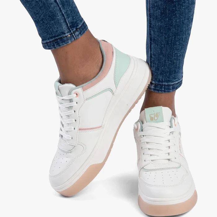 Sissy Boy white low-top sneakers with multi pastel accents on a person wearing blue jeans, captured from a low angle.