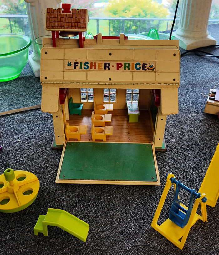 Fisher-Price wooden playset on a carpeted floor with additional toys around.
