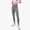 Woman models dark grey adidas Women's Te 7/8 Tights and a white sports bra, standing front-facing.